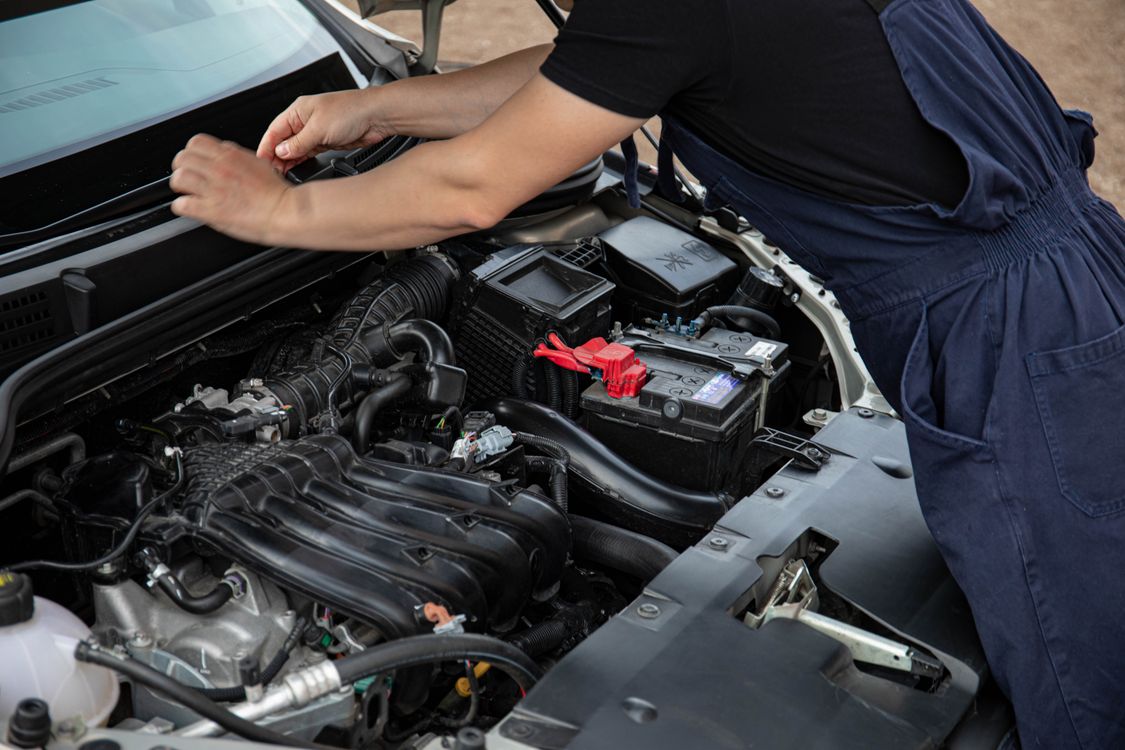 Mobile mechanic servicing a car outdoors, working under the hood